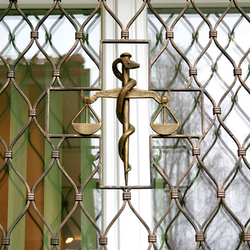 Kované váhy ako symbol lekárstva na okenných mrežiach - detail